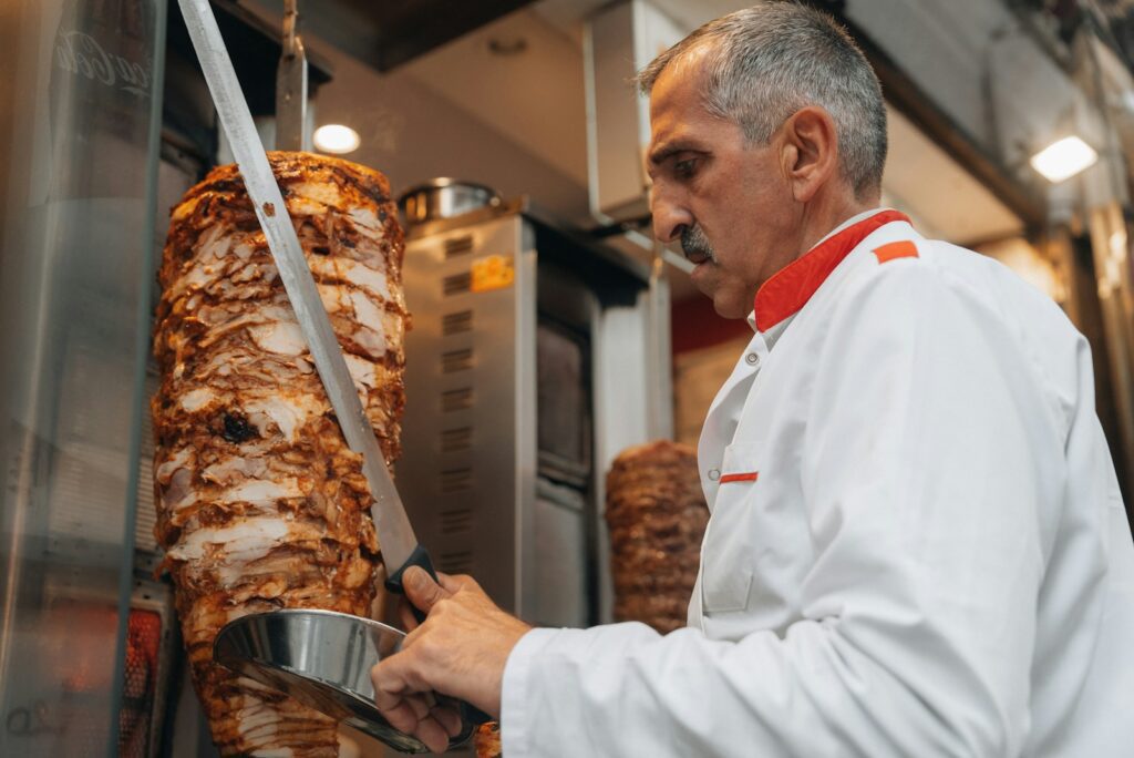 a man cutting a large piece of meat in a kitchen