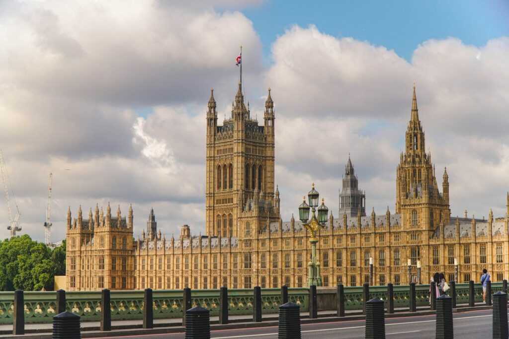 The houses of parliament stand under a cloudy sky.